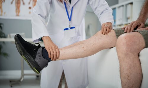 Physiotherapist checking hurt leg of senior man